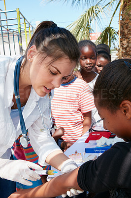 Buy stock photo Shot of a volunteer nurse giving injections to underprivileged kids