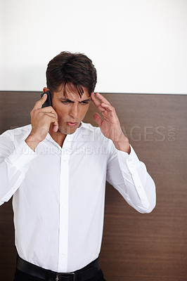 Buy stock photo Shot of a young businessman looking furious while talking on the phone