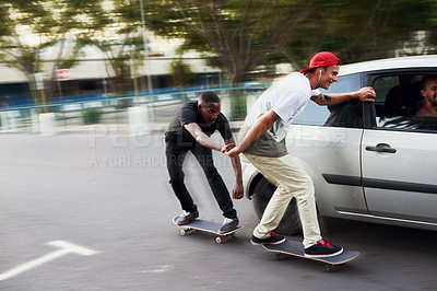 Buy stock photo Shot of two skaters holding on to a moving car