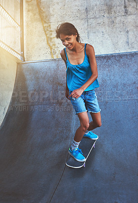 Buy stock photo Shot of a young woman doing tricks on her skateboard at the skatepark