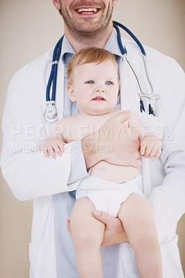 Buy stock photo A male doctor holding an infant patient in his arms