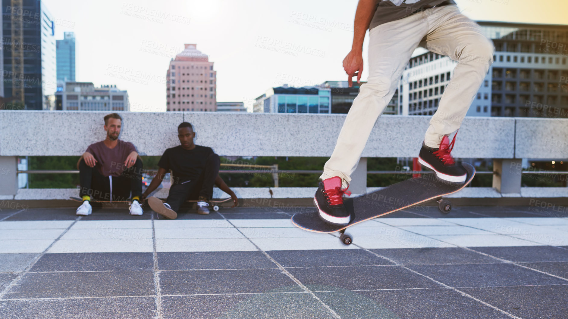 Buy stock photo Shot of a young man doing tricks on his skateboard while his friends looks on