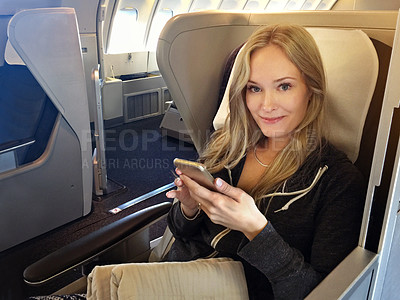 Buy stock photo Portrait of a young woman using her cellphone while sitting in first class in an airplane