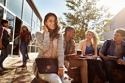 Buy stock photo Shot of a student sitting outside on campus with her friends blurred in the background