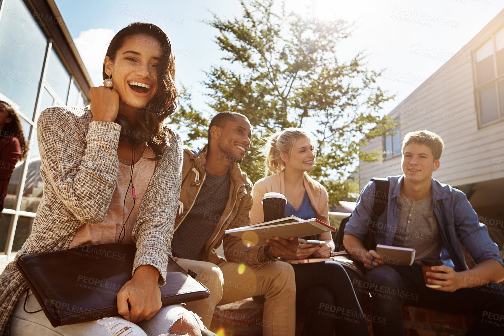 Buy stock photo Shot of a student sitting outside on campus with her friends blurred in the background