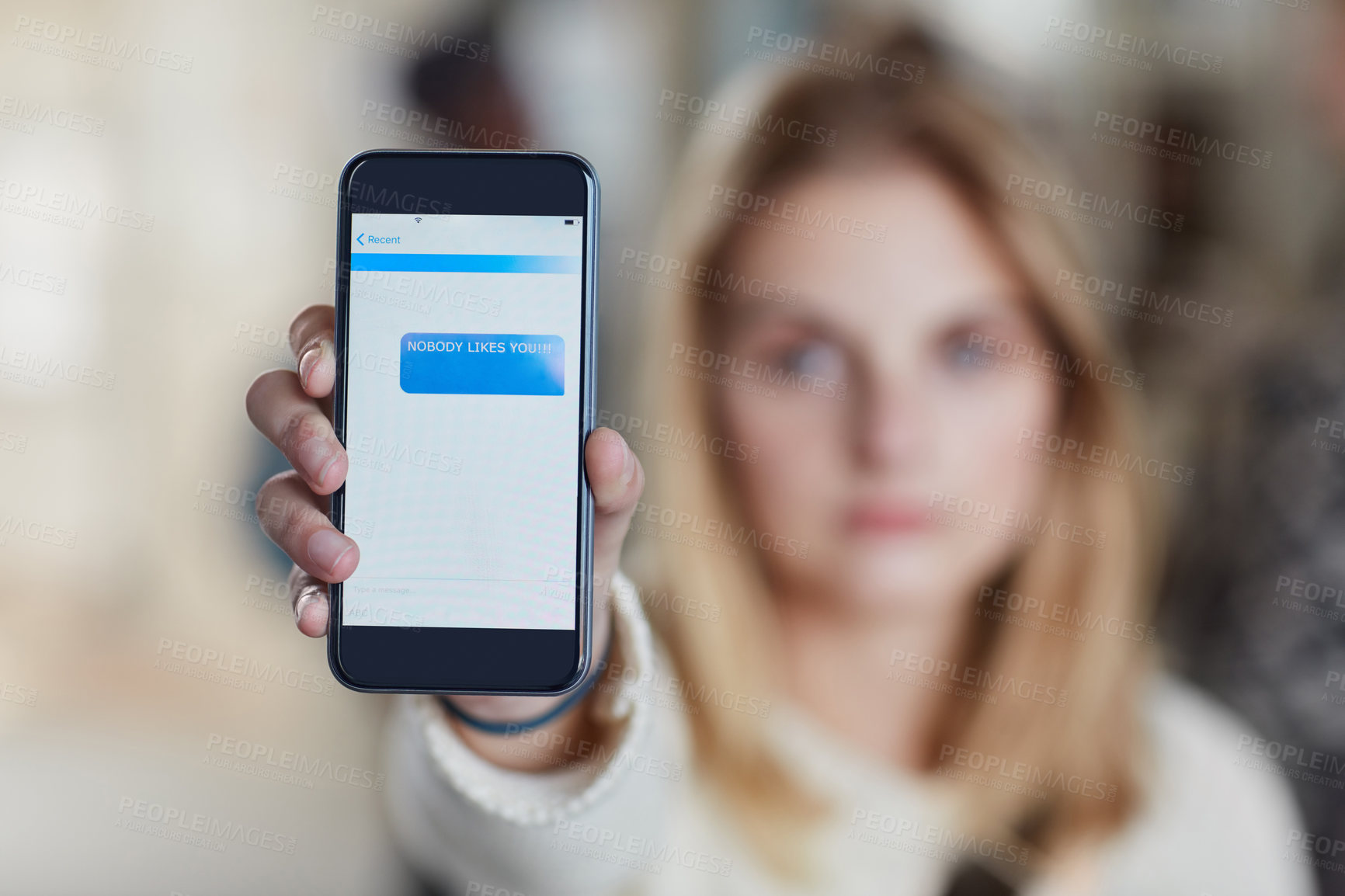 Buy stock photo Closeup shot of a university student holding up a cellphone with a rude text message