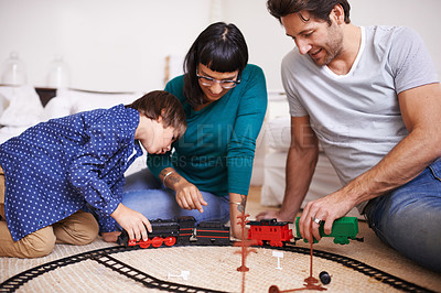 Buy stock photo Shot of a young family setting up a toy train set