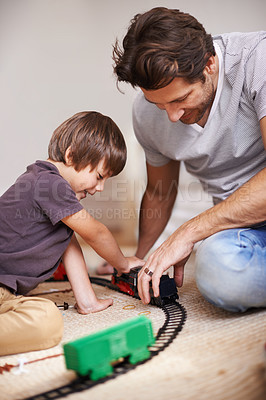Buy stock photo Man, boy and playing with train toys, together for family time and fun with plastic railway track at home. Father, child and excited youth for games, playful and happiness with bonding in playroom 