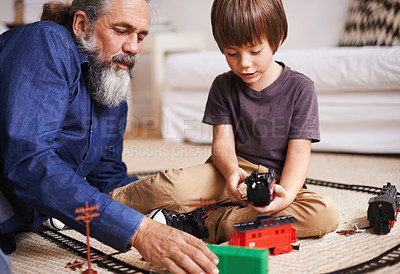 Buy stock photo Cropped shot of a grandfather watching his grandson play with a toy train