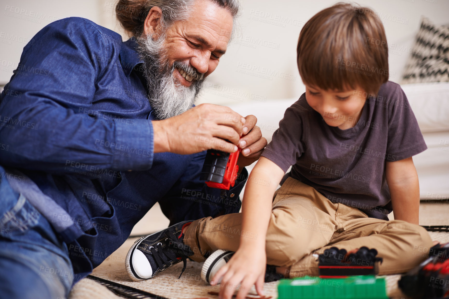 Buy stock photo Grandfather, laugh and toy train with boy child, playing and bonding in family lounge. Grandpa, young kid and childhood development with games and fun, quality time and love with elderly retired man 