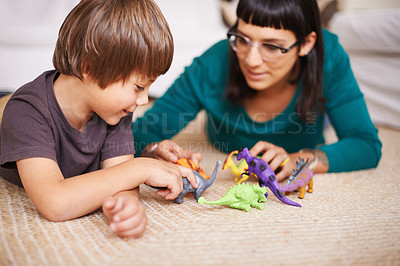 Buy stock photo Cropped shot of a mother and her son playing with toy dinosaurs