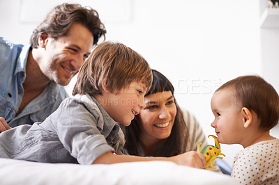 Buy stock photo Family, love and toy for play in bedroom, support and happy for childhood in home on bed. Parents, children and security in connection or plastic animal, care and relax on weekend or game for bonding