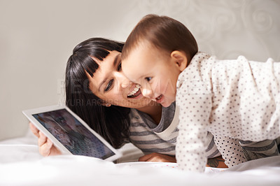 Buy stock photo Shot of a happy mother showing her baby daughter a digital tablet