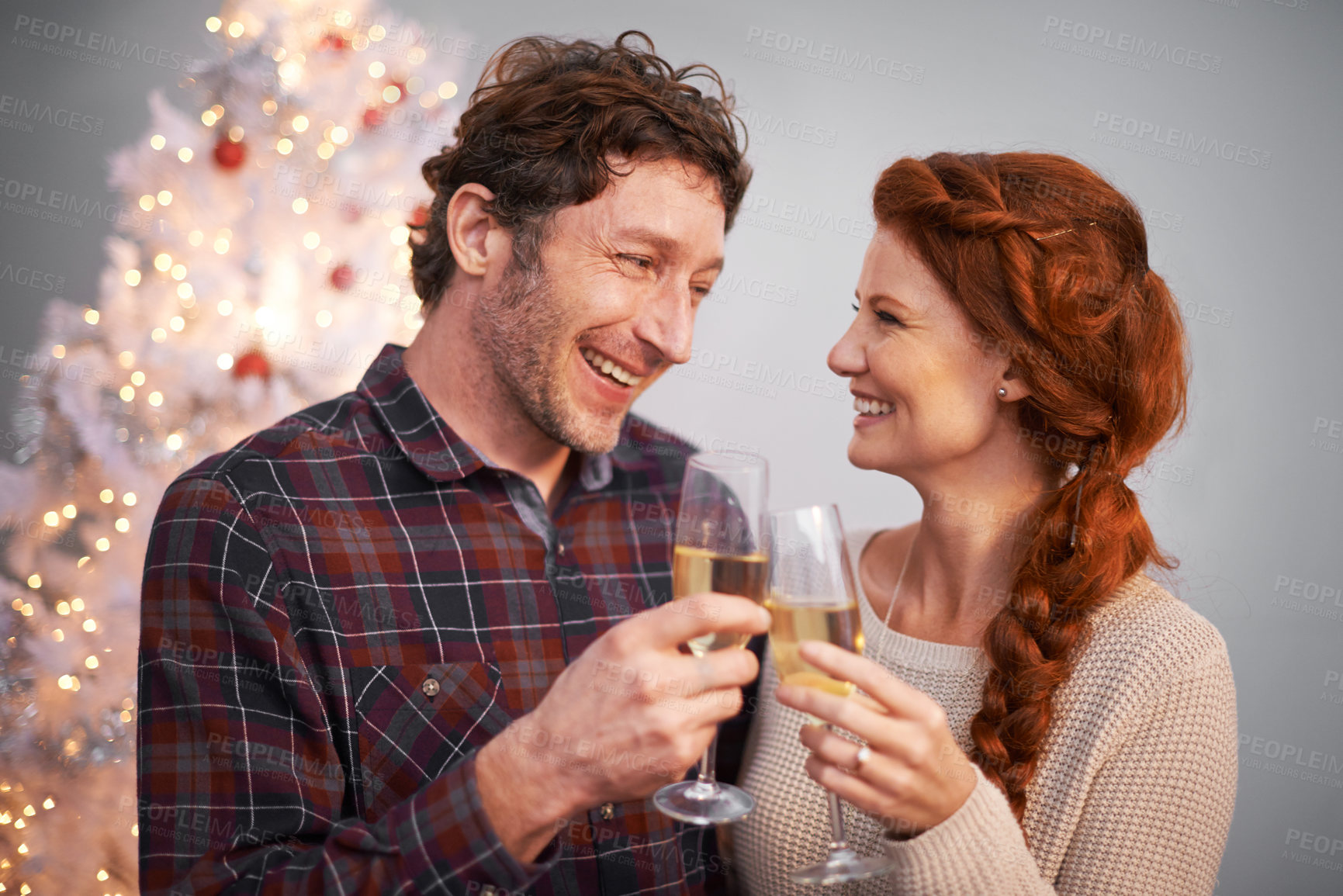 Buy stock photo Shot of an affectionate couple enjoying some champagne at Christmas