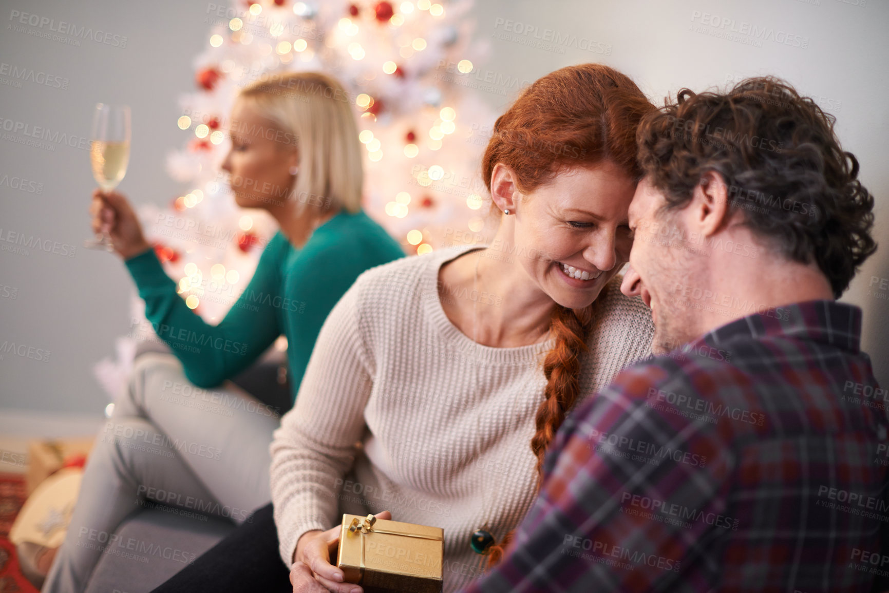 Buy stock photo Christmas, gift and couple embrace with love for holiday in home, smile and happiness. Marriage, woman and man as husband and wife in house for celebration of festive, season and romance on vacation