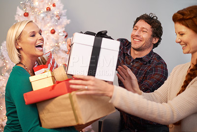 Buy stock photo Friends, Christmas and gift box for celebration at tree for festive season or giving present, vacation or together. Man, women and parcel in living room for winter break or excited, bonding or love