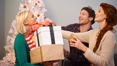 Buy stock photo Friends, Christmas and present for celebration at tree for festive season or giving gift box, vacation or holiday. Man, women and parcel in living room for winter break or excited, bonding or love