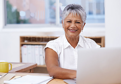 Buy stock photo Portrait of a mature businesswoman using her laptop while sitting at her desk