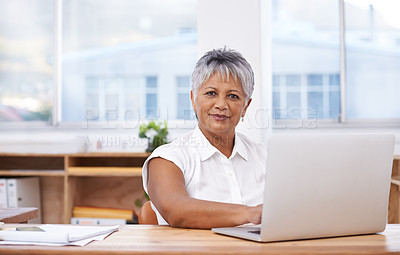 Buy stock photo Portrait of a mature businesswoman using her laptop while sitting at her desk
