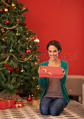 Buy stock photo Shot of an attractive young woman holding out her Christmas gift