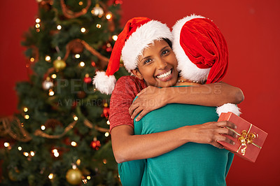 Buy stock photo Women, hug and Christmas with surprise, gift box and package on red studio background. Face, people or friends with Xmas present or parcel with embrace or excited with celebration or bonding together