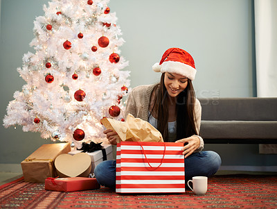 Buy stock photo Cropped shot of an attractive young woman opening her Christmas gift