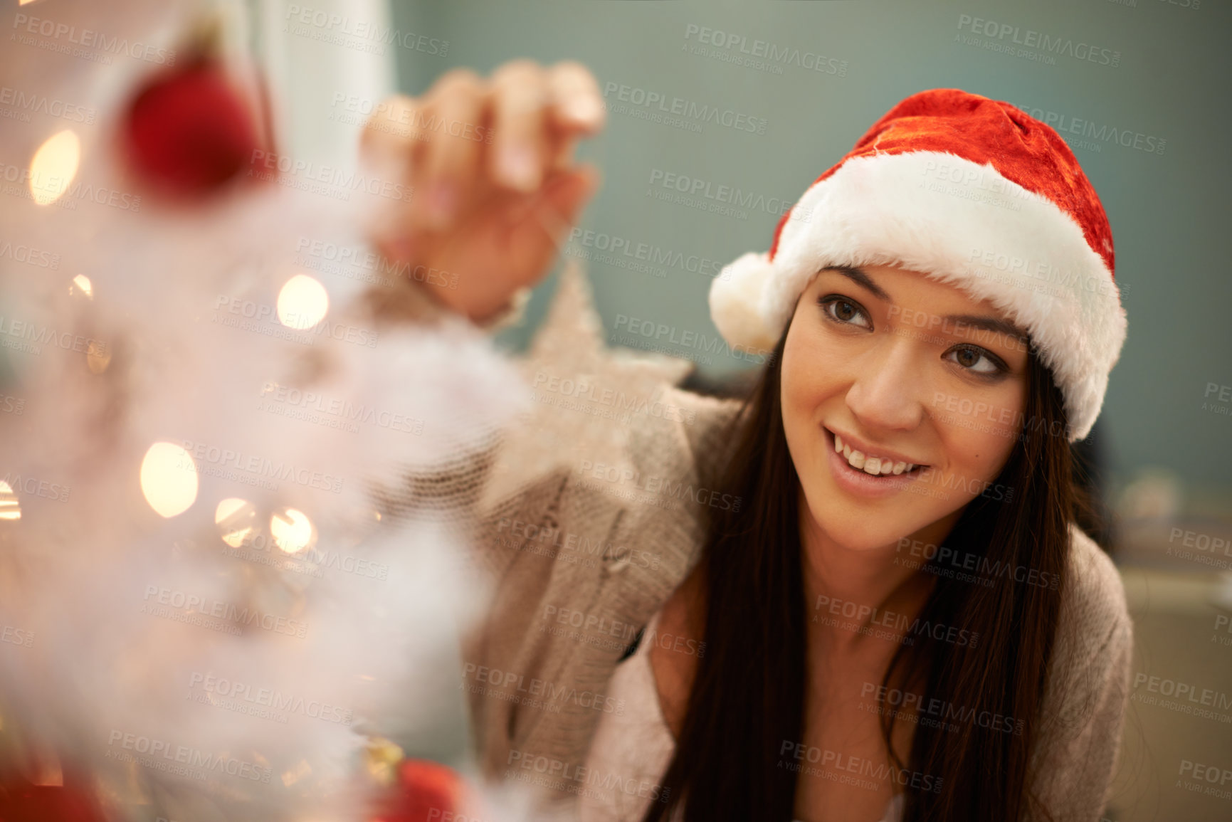 Buy stock photo Cropped shot of an attractive young woman decorating a Christmas tree