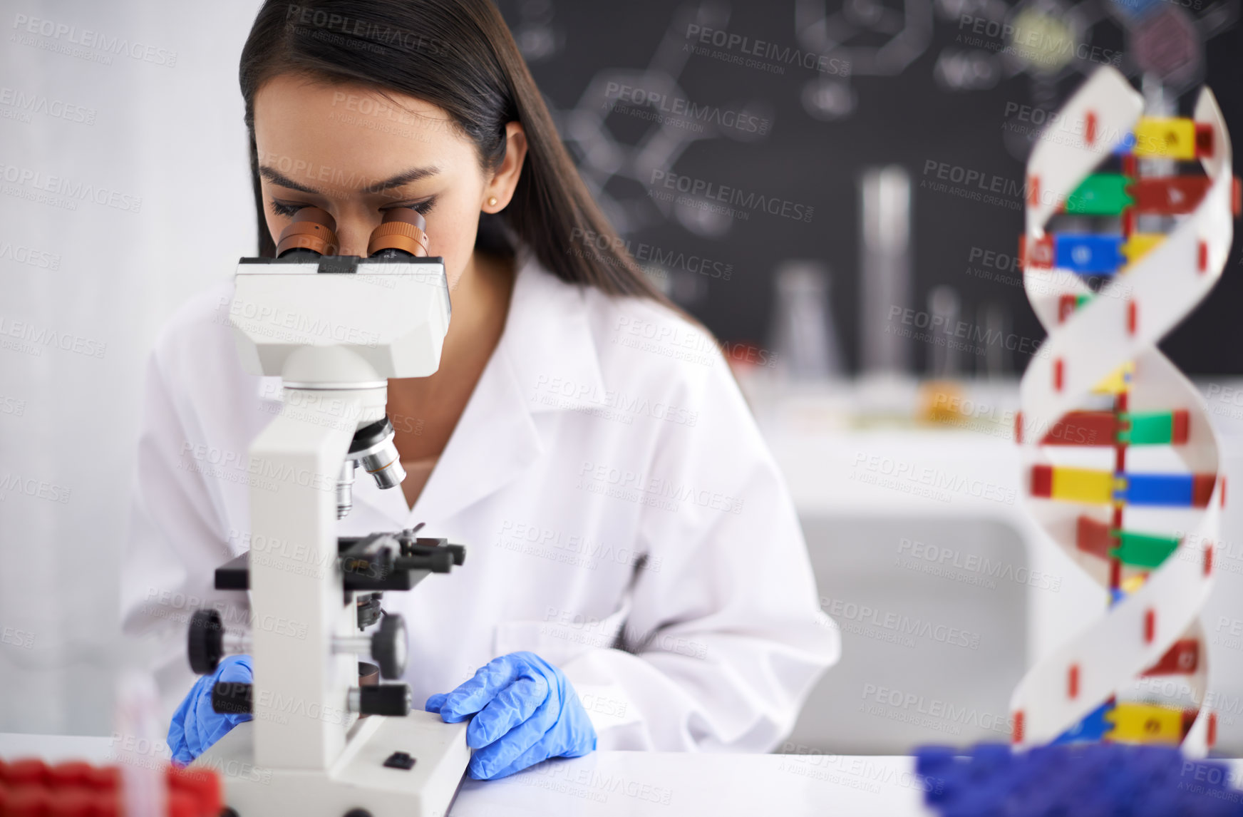 Buy stock photo Profile of a female scientist viewing a sample through a microscope