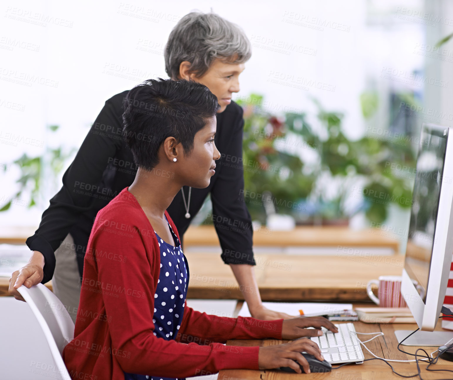 Buy stock photo Shot of two female colleagues discussing work on a desktop computer