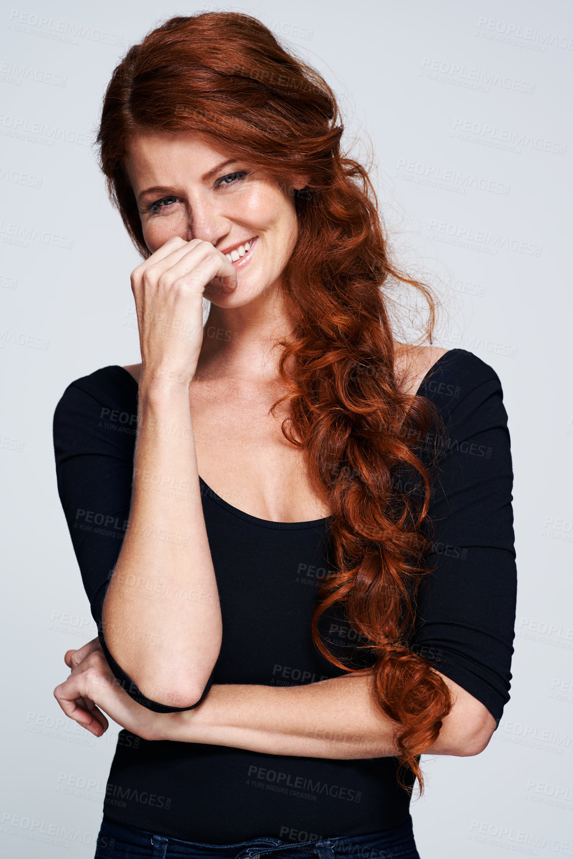 Buy stock photo Studio shot of a young woman with beautiful red hair posing against a gray background