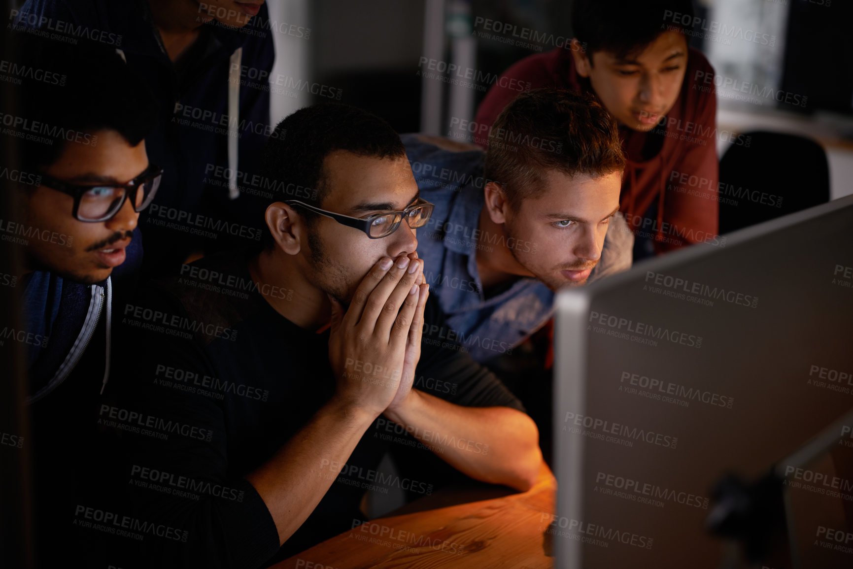 Buy stock photo Shot of a group of young designers staring tensely at a monitor