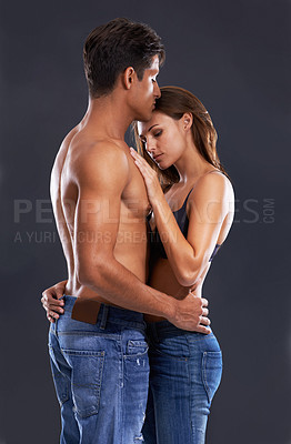 Buy stock photo Studio shot of a passionate couple embracing against a gary background