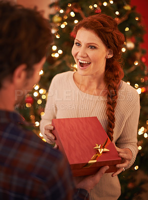 Buy stock photo Shot of a young woman excitedly receiving a gift