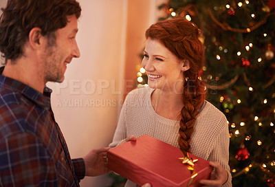 Buy stock photo Couple, tree for Christmas and gift to celebrate holiday, festive season of giving for love and commitment. Happy, gratitude and support with people at home for present, romance and relationship