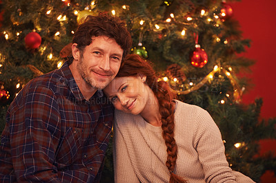 Buy stock photo Portrait of an affectionate young couple sitting by their Christmas tree