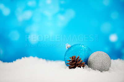 Buy stock photo Arranged Christmas decorations on a white surface against a sparkly blue background. Simple festive scene of silver baubles and pinecone on a textured wallpaper. Shine and cheer for holiday joy