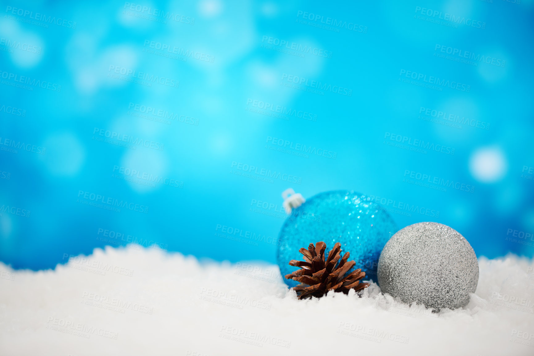 Buy stock photo Arranged Christmas decorations on a white surface against a sparkly blue background. Simple festive scene of silver baubles and pinecone on a textured wallpaper. Shine and cheer for holiday joy