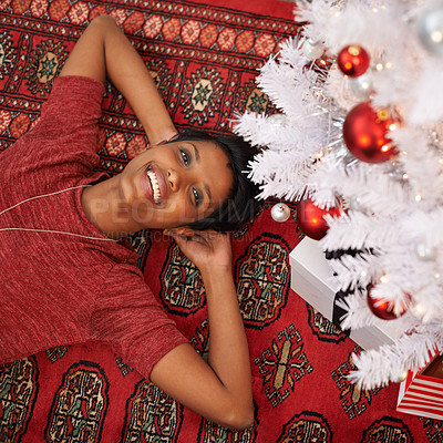 Buy stock photo A portrait of a beautiful young woman lying underneath her Christmas tree at home