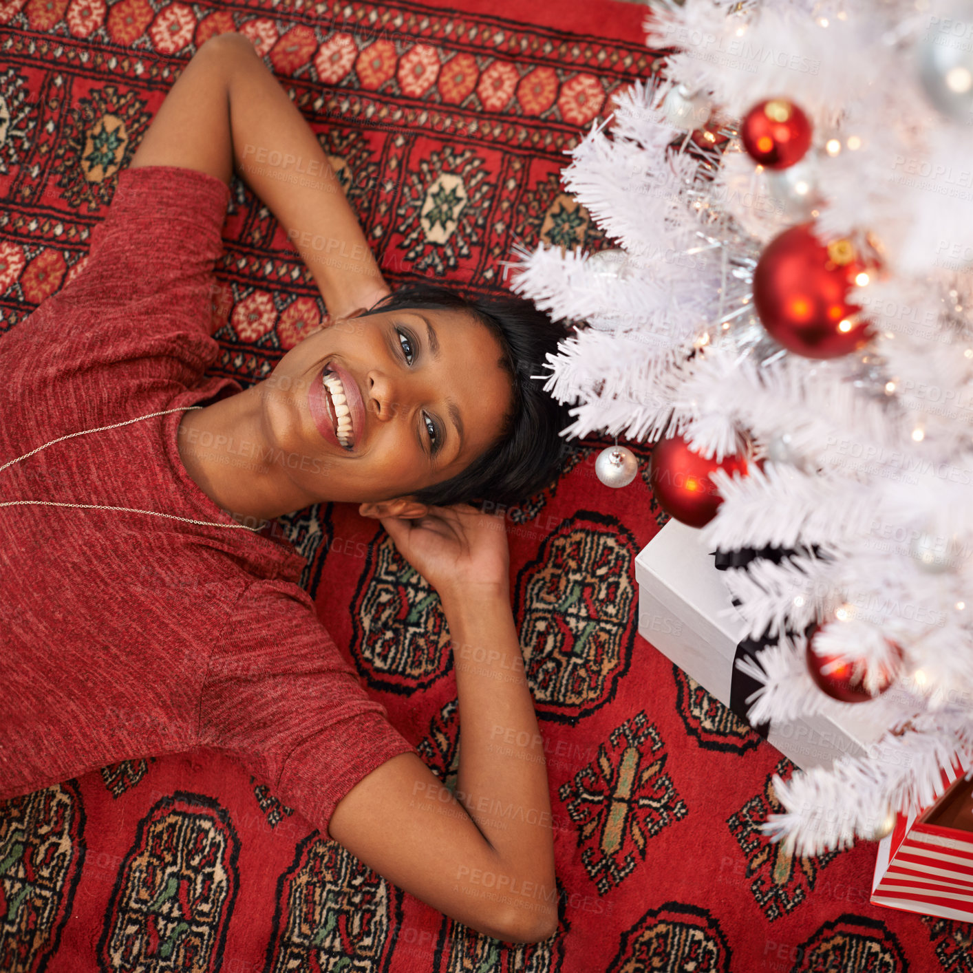 Buy stock photo A portrait of a beautiful young woman lying underneath her Christmas tree at home