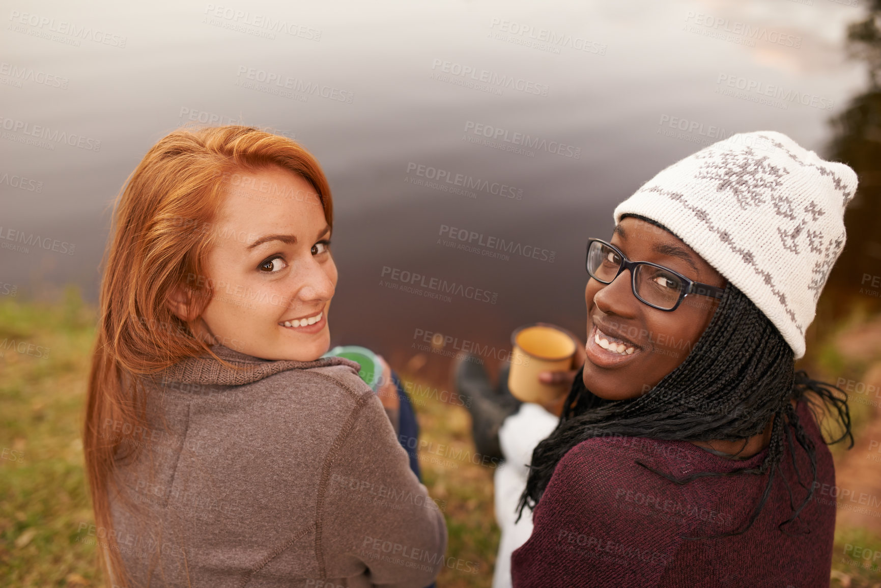 Buy stock photo High angle portrait of two happy teenage girls sitting beside a lake