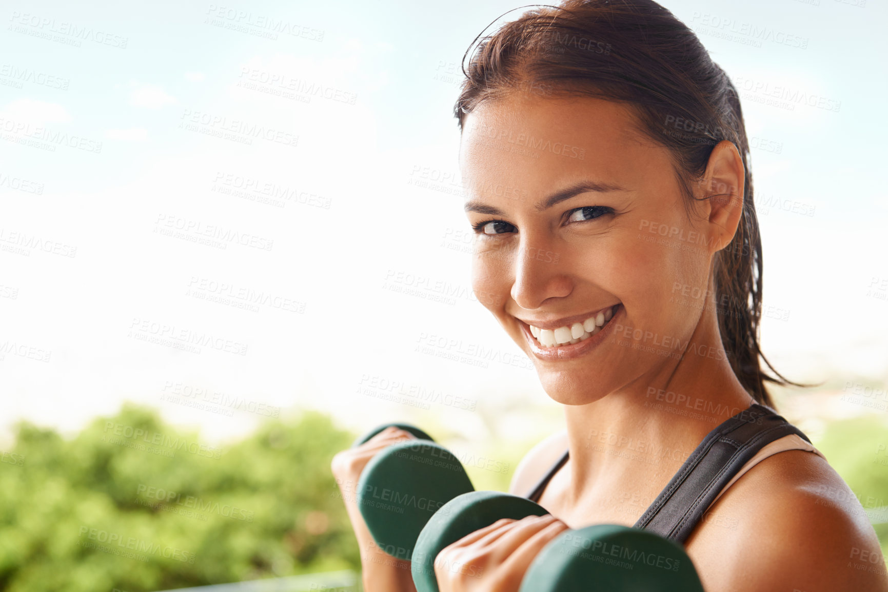 Buy stock photo Portrait of a sporty young woman working out with dumbbells