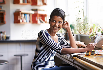 Buy stock photo A young woman sitting in a coffee shop with a newspaper in her hand