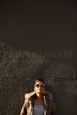 Buy stock photo Cropped shot of an attractive young woman leaning against a wall