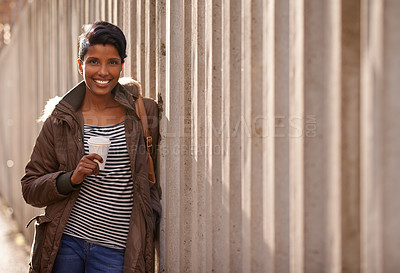 Buy stock photo A portrait of a beautiful young woman leaning against a concrete wall in the city