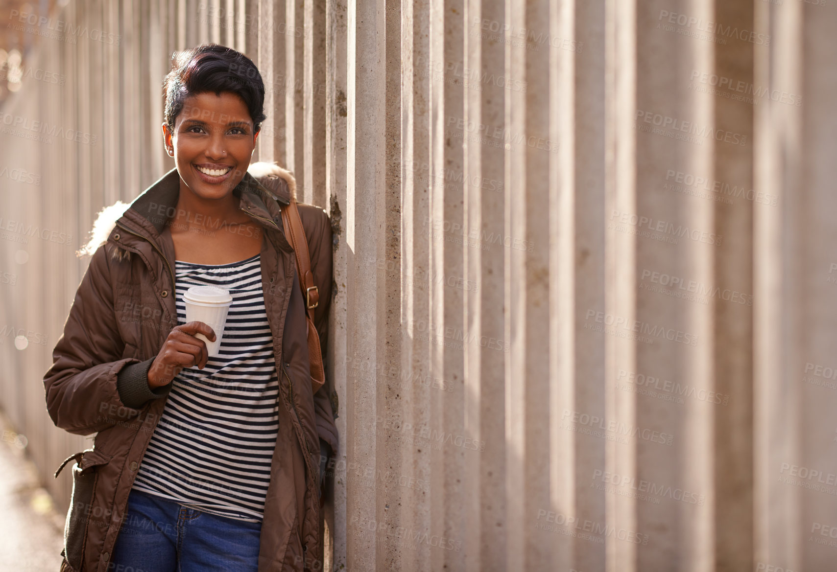 Buy stock photo A portrait of a beautiful young woman leaning against a concrete wall in the city