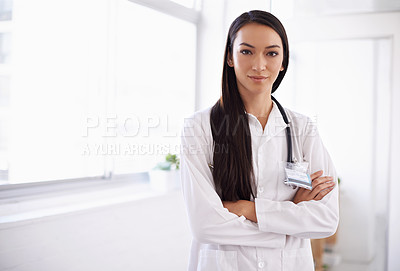 Buy stock photo Portrait of a confident young doctor standing with her arms folded