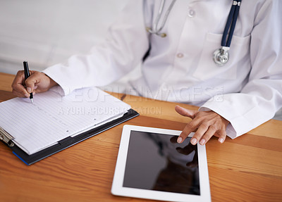 Buy stock photo Cropped shot of a doctor using a digital tablet and writing on a sheet of paper