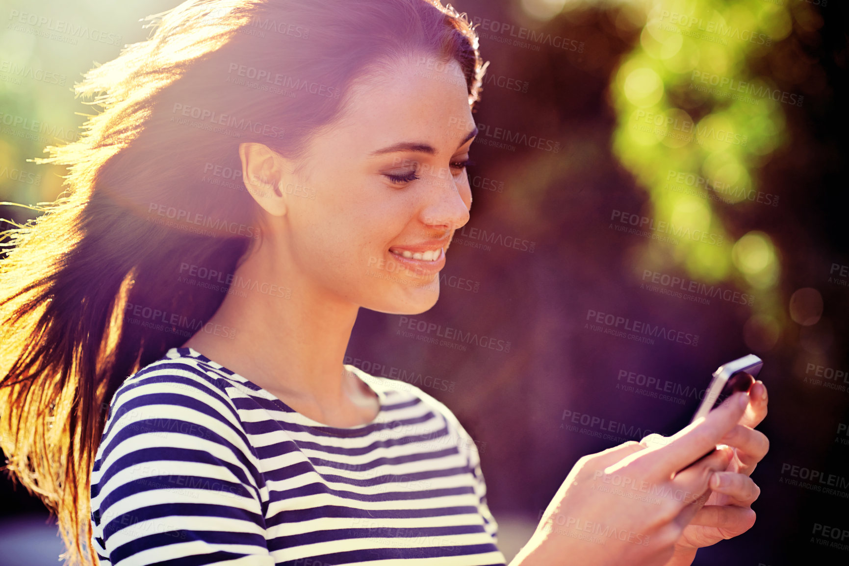 Buy stock photo Shot of a beautiful young woman using a mobile phone in the outdoors