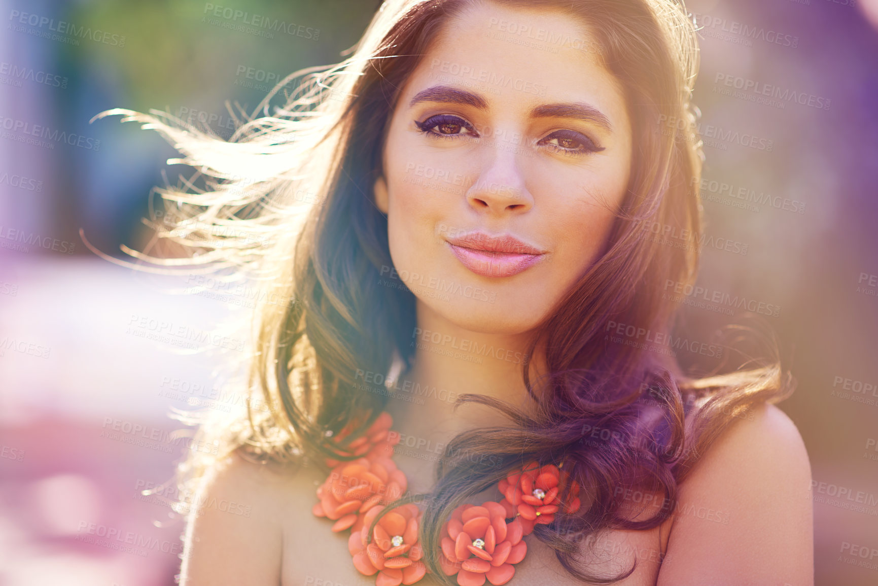 Buy stock photo Portrait of a trendy young woman wearing fashionable accessories while standing outside. The face of a beautiful lady wearing a chunky orange flower necklace and perfect makeup on a sunny day outside