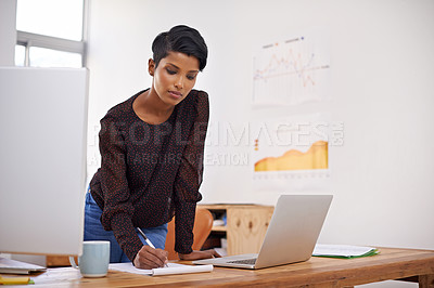 Buy stock photo A beautiful young woman making notes in her office